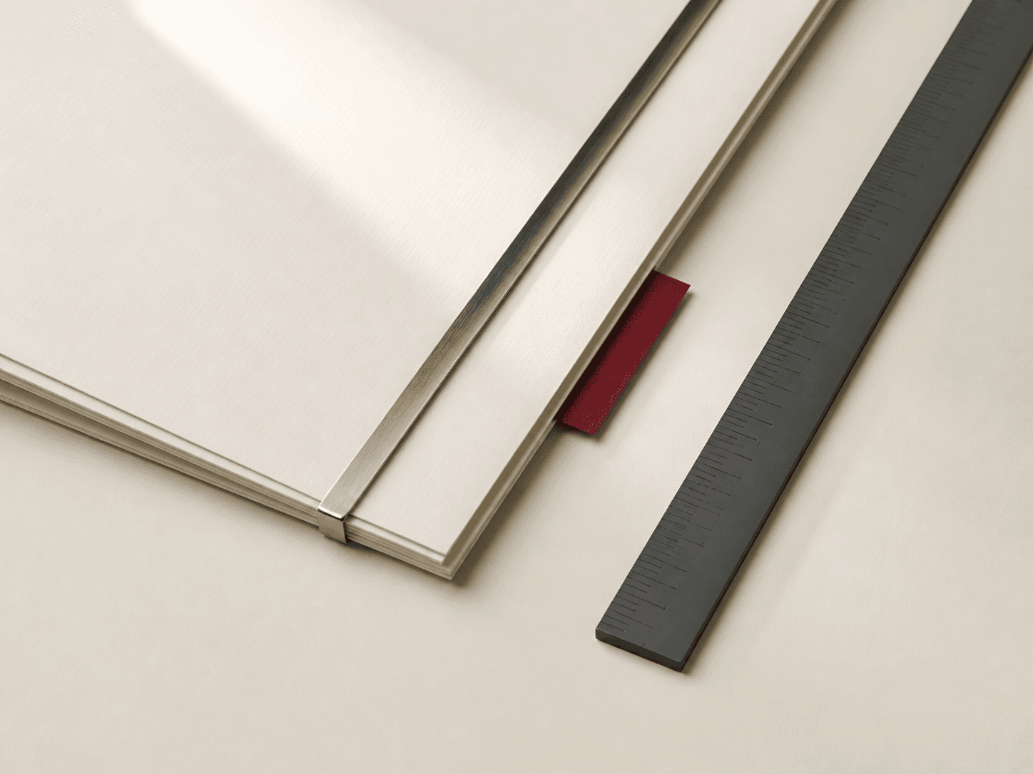 Precisely aligned ivory papers, a metal binding bar, and a graphite rule.