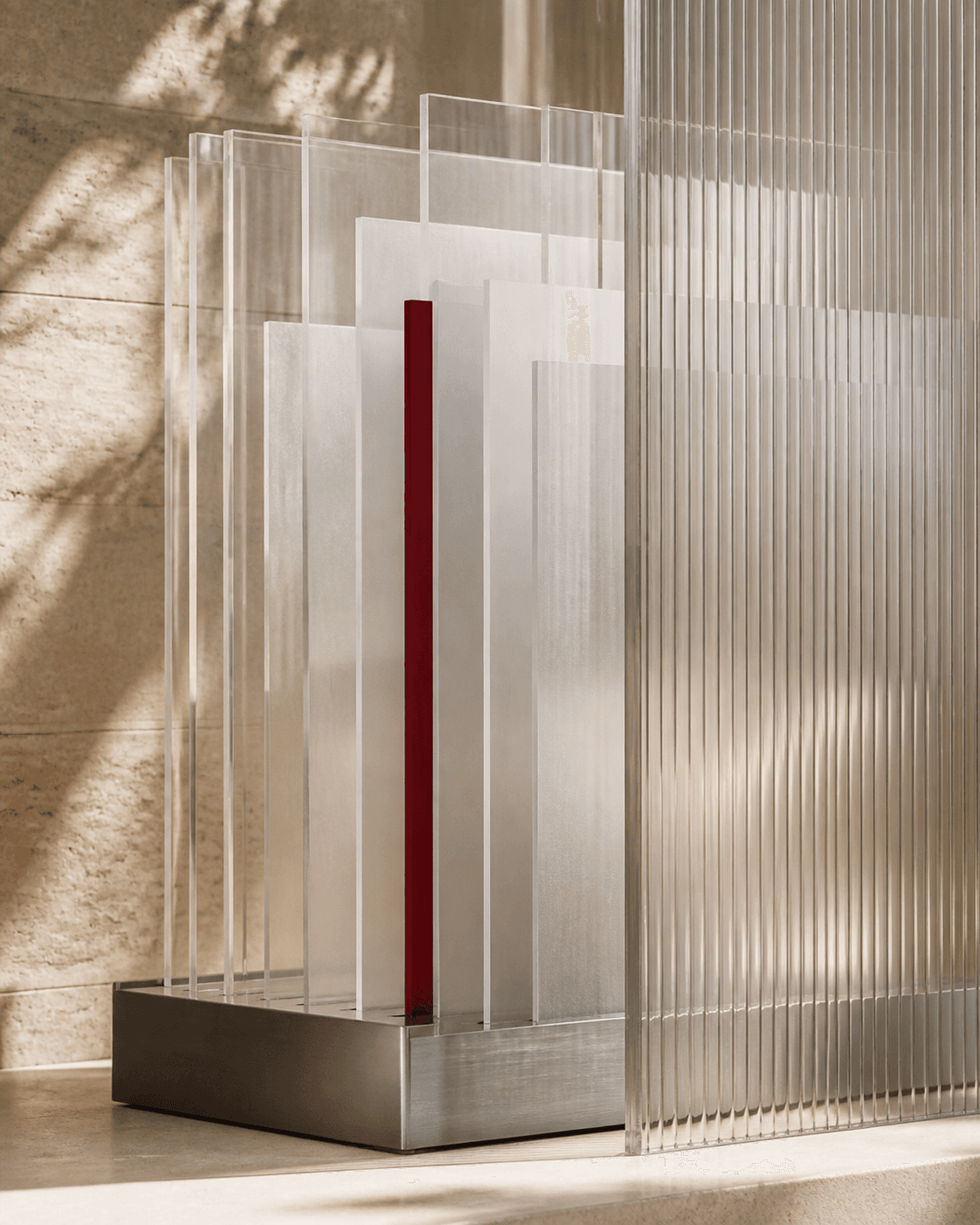 Layered translucent panels held in a metal track beside ribbed glass.