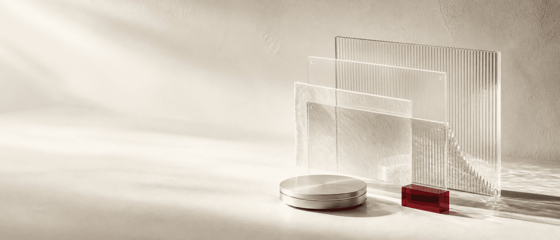 Layered clear panels and a red signal block beside a brushed-metal disc