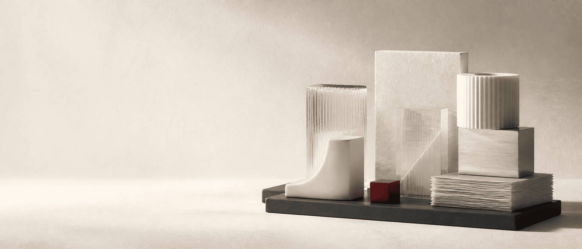 Six ivory, glass and graphite forms arranged as one modular system, with a small carmine accent.